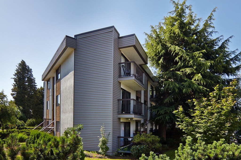 a picture of a gray apartment building with a blue sky in the background