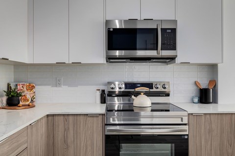 A modern kitchen with a stainless steel oven and microwave above it.