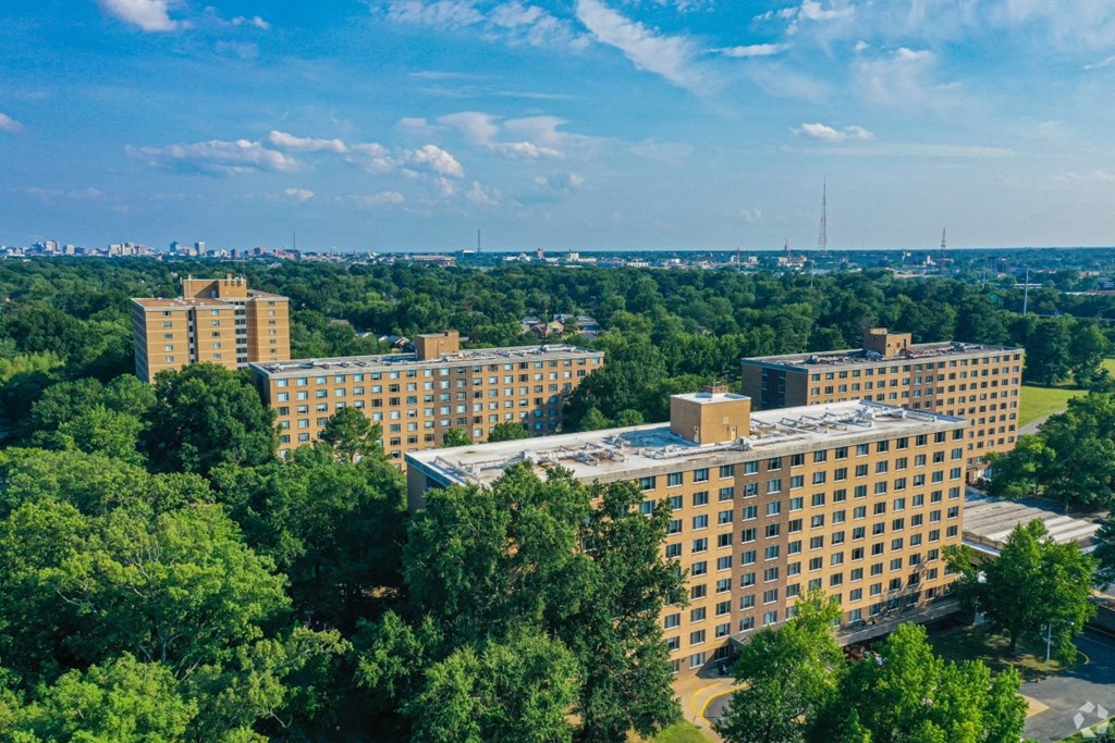 A large building complex surrounded by trees under a blue sky.