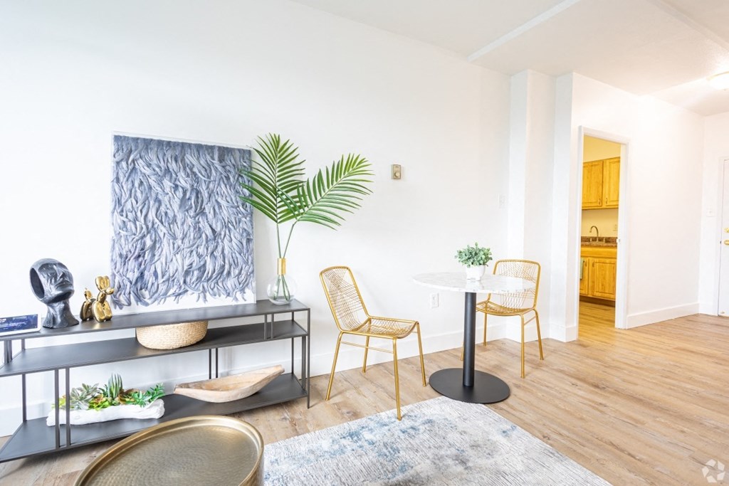 A living room with a blue rug, a yellow chair, and a plant.