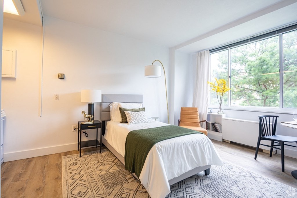 A bedroom with a large bed and a chair by the window.