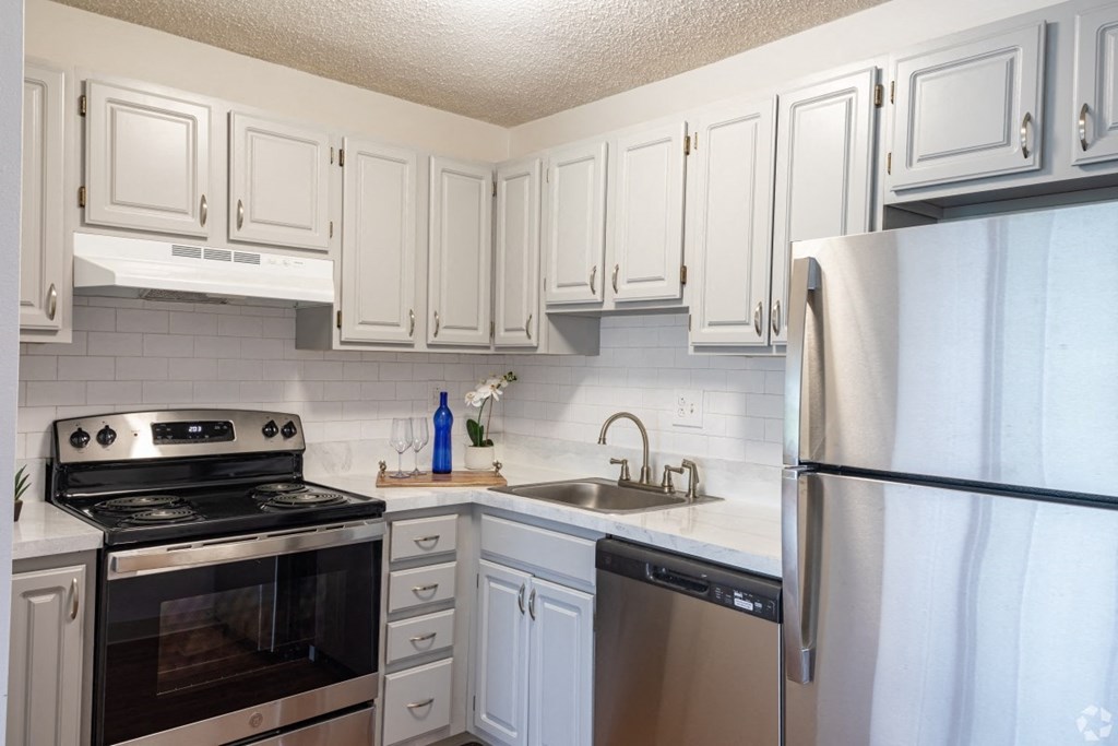 A kitchen with white cabinets and a stainless steel refrigerator.