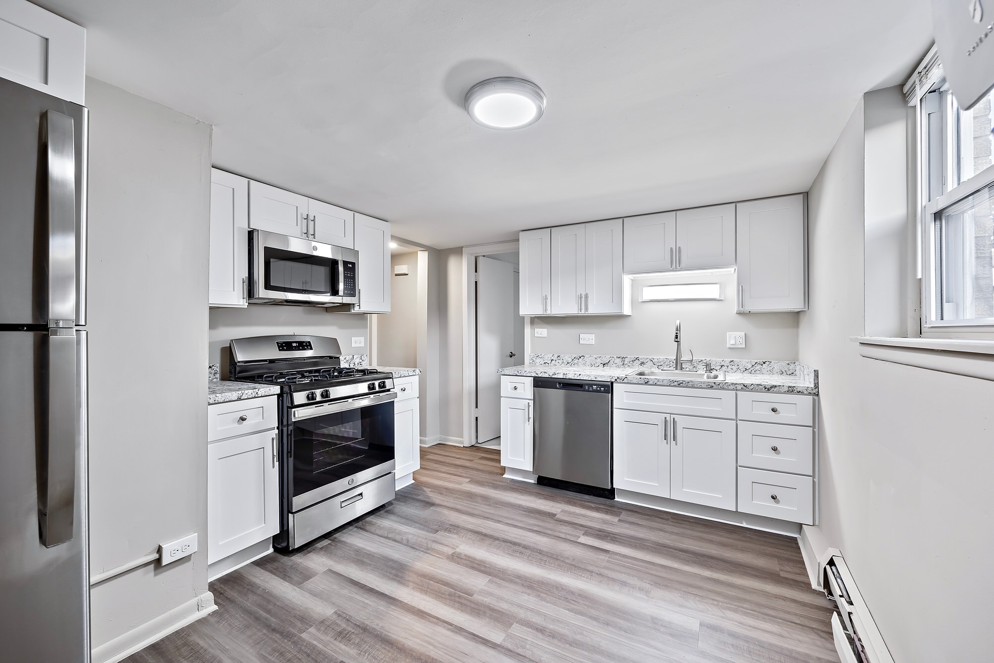 A kitchen with a refrigerator, oven, and microwave.