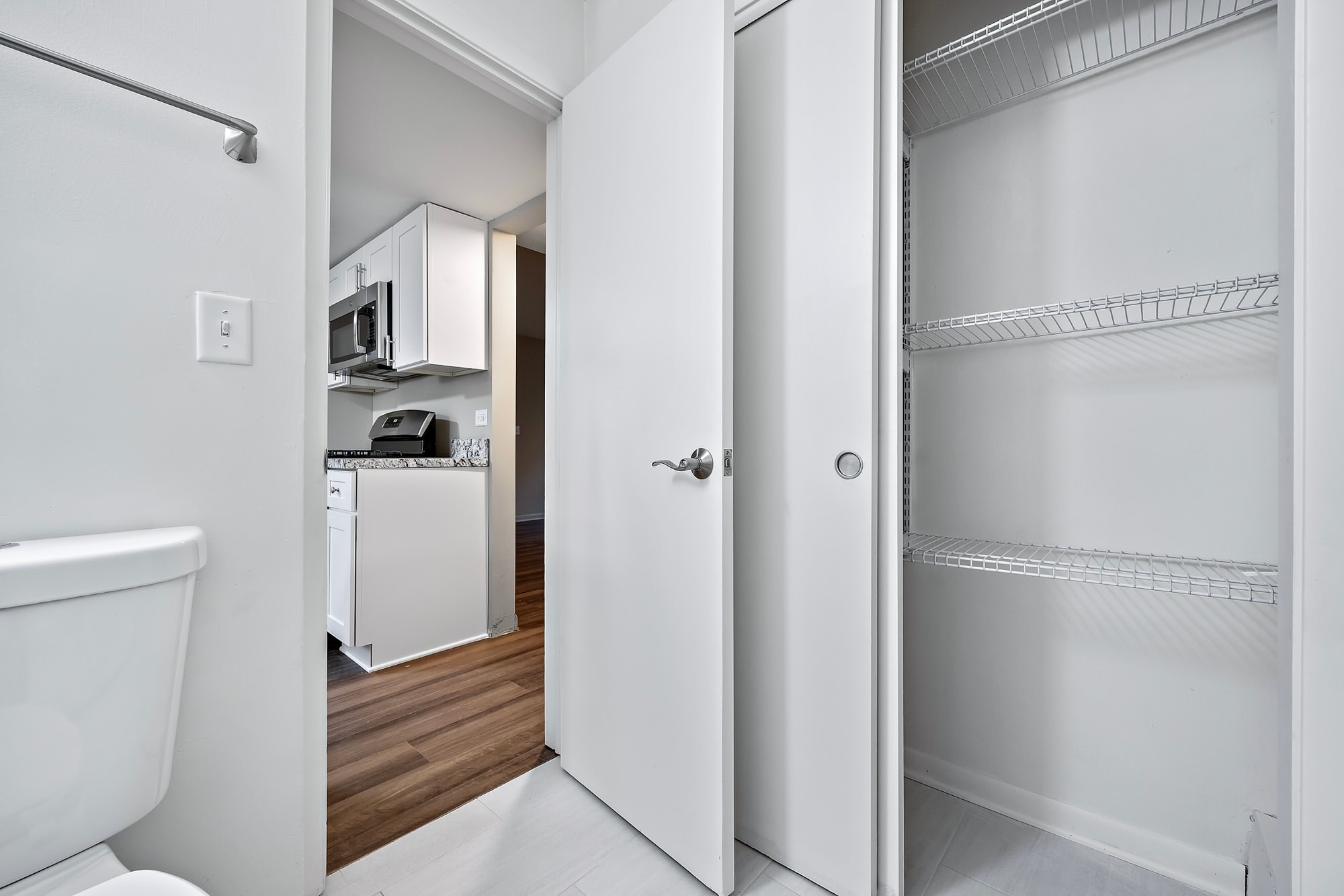 A white refrigerator is in a kitchen with a white toilet.
