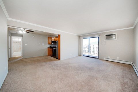 A spacious living room with a carpeted floor and sliding glass doors leading to a balcony.
