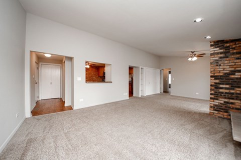 A spacious room with a carpeted floor and a brick wall on one side.