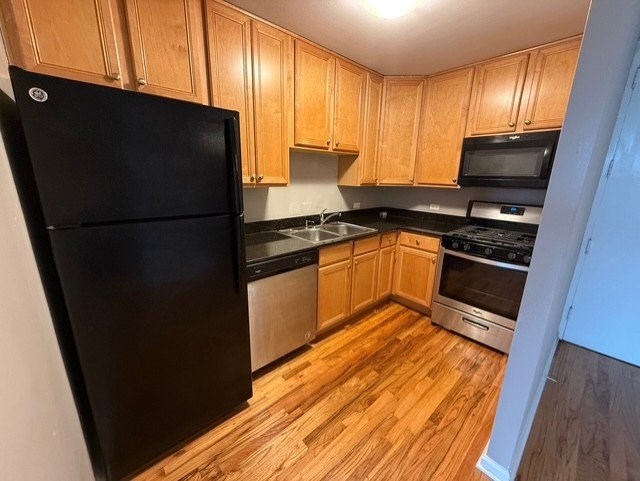 A kitchen with wooden cabinets and a black refrigerator.