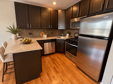 A modern kitchen with dark wood cabinets and stainless steel appliances.