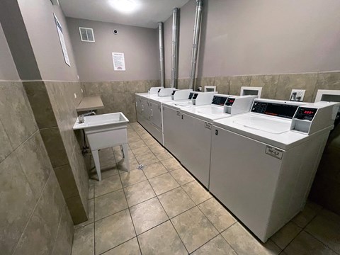 a laundry room with four washing machines and three sinks