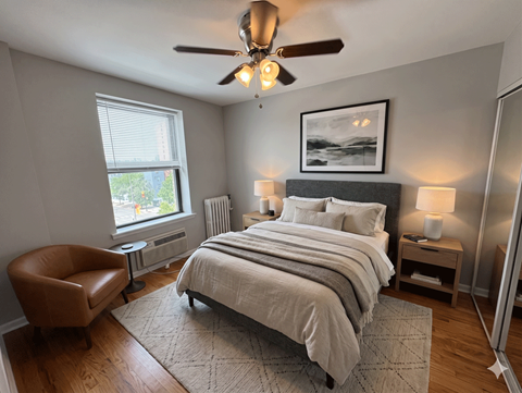 A bedroom with a large bed, a chair, and a ceiling fan.