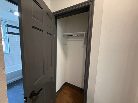 A white wall with a black door and a white shelf.