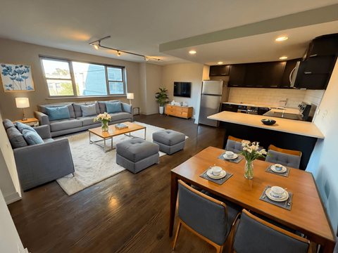 A modern living room with a grey couch and a wooden dining table.