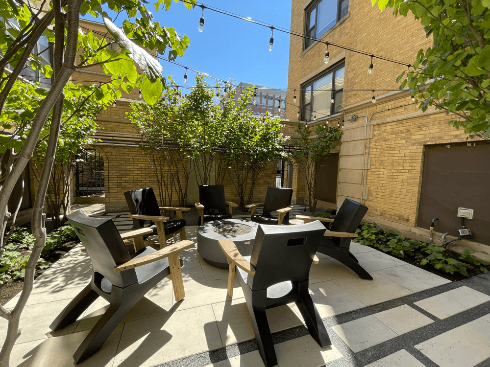 a courtyard with tables and chairs and a fire pit