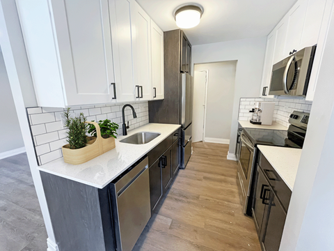 a renovated kitchen with white cabinets and stainless steel appliances