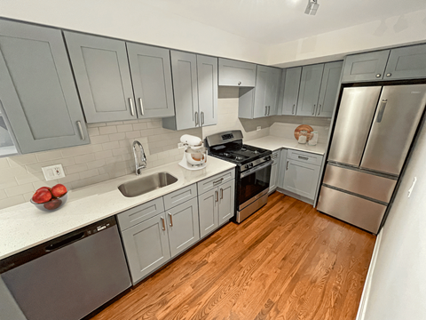 a renovated kitchen with gray cabinets and stainless steel appliances