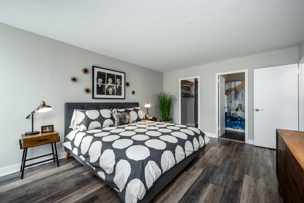 A bedroom with a bed, nightstand, and a plant at The Bryn - 5600 N Sheridan Rd Apartments, Illinois, 60660