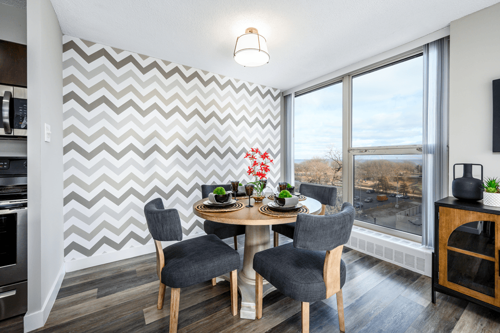 A dining room with a chevron patterned wallpaper and a round wooden table with four chairs at The Bryn - 5600 N Sheridan Rd Apartments, Chicago