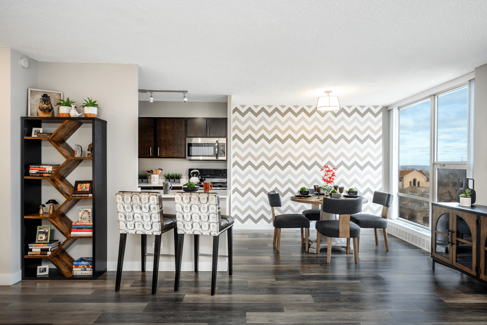 A modern dining room with a chevron patterned wallpaper and a wooden dining table set with chairs at The Bryn - 5600 N Sheridan Rd Apartments, Illinois