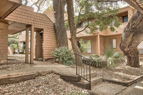 A brick house with a tree in front.