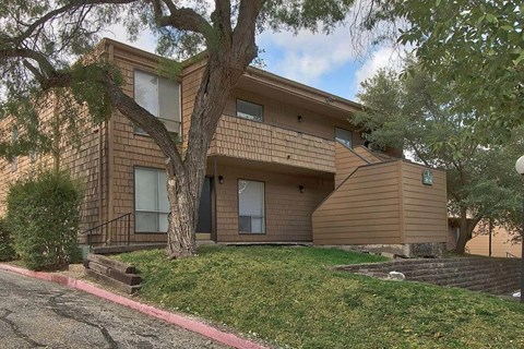 A brown house with a tree in front of it.