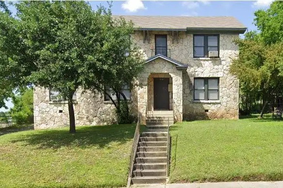 A house with a stone facade and a brown door.