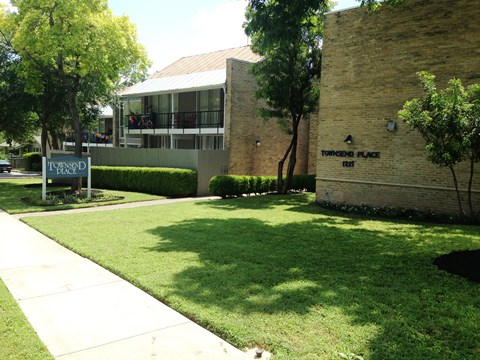 A sign for Torrance Place stands in front of a brick building.
