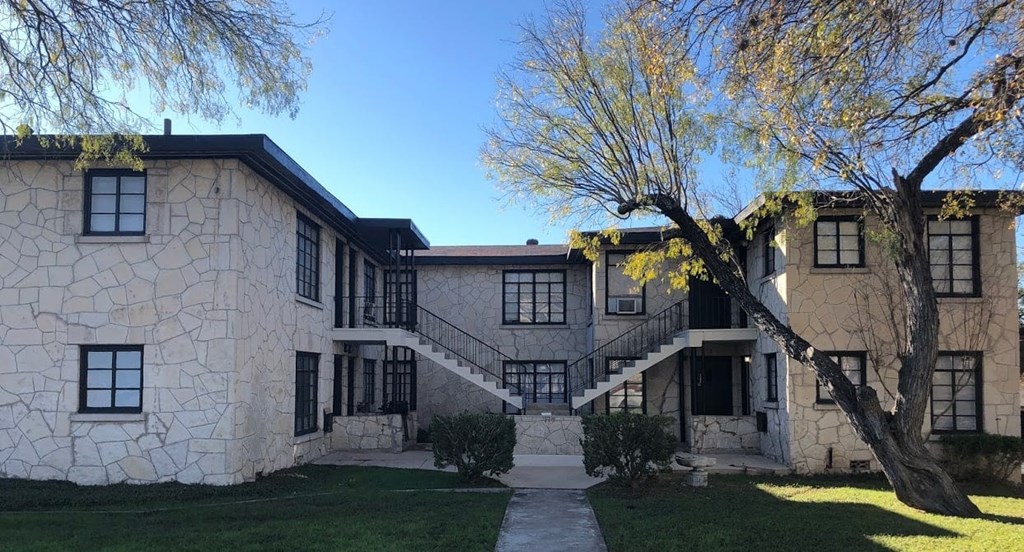 A large house with a stone exterior and a tree in front.