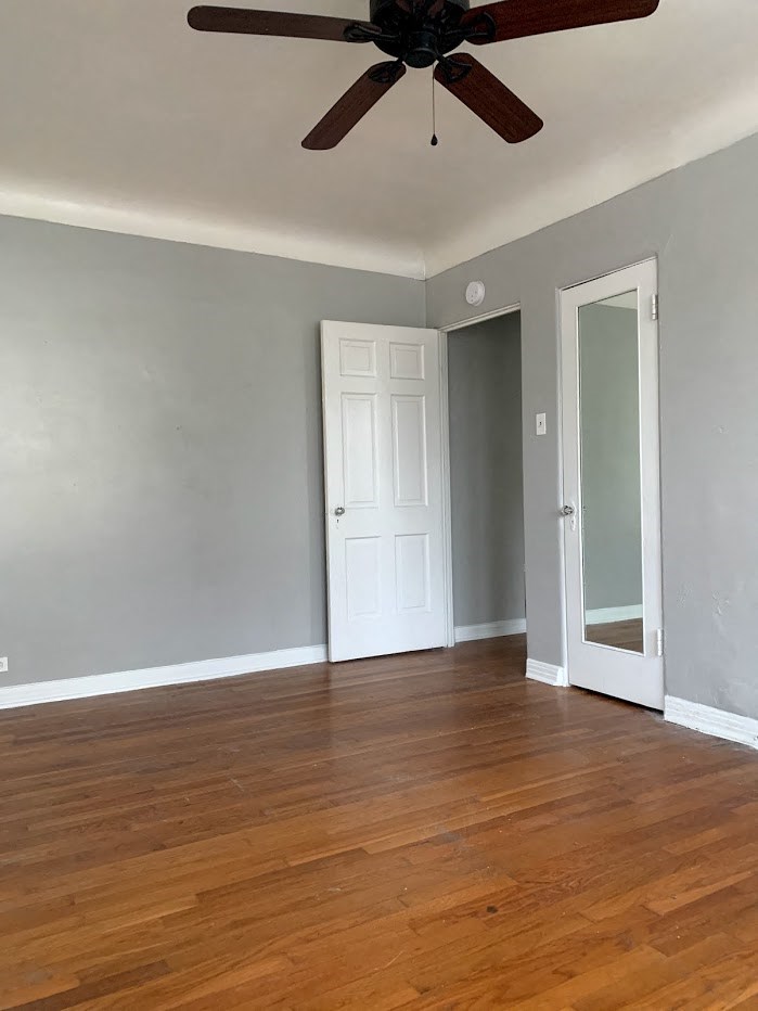 A room with a ceiling fan and wooden floors.