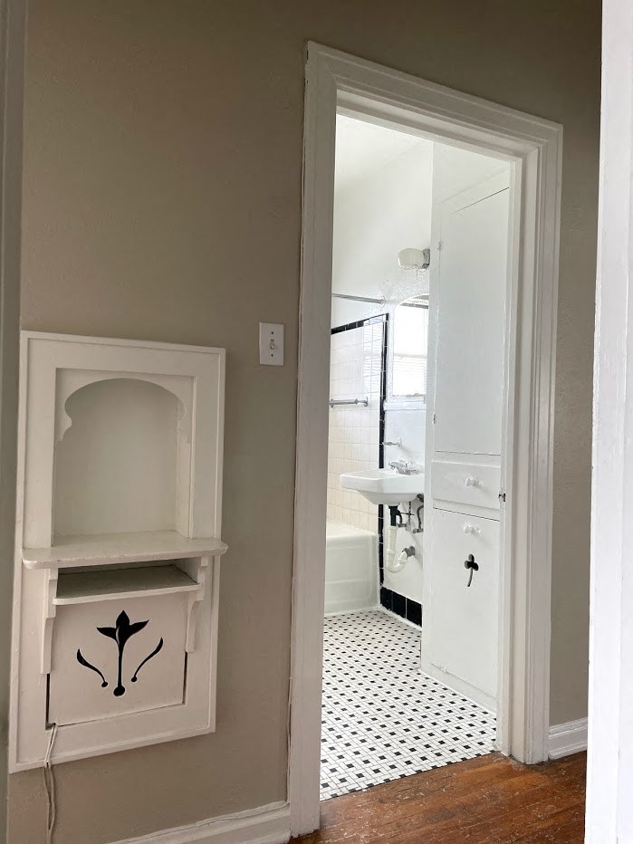 A white bathroom with a white door and a white cabinet.