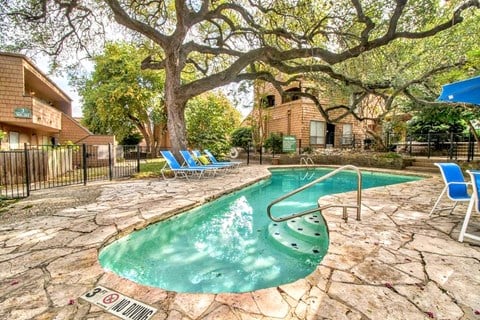 the pool is surrounded by chairs and a tree