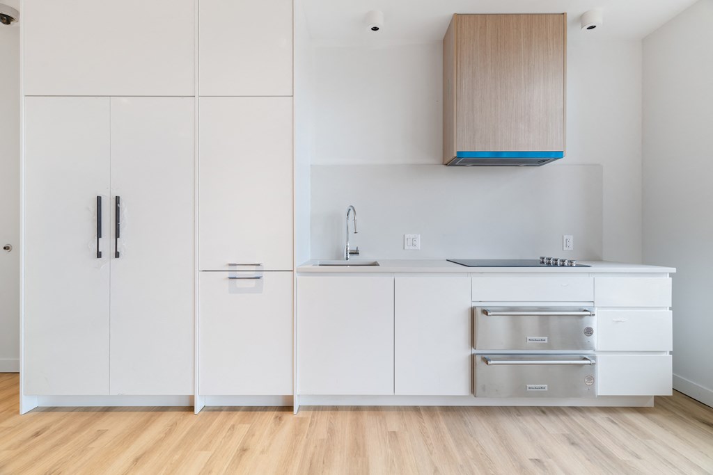 a kitchen with white cabinets and a stainless steel oven and sink