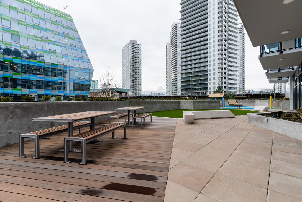 a terrace with tables and benches on a roof with skyscrapers