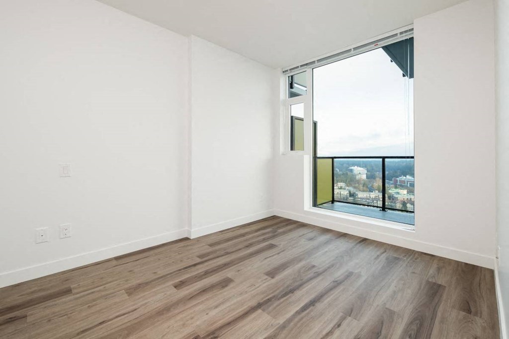 an empty living room with wood floors and a window