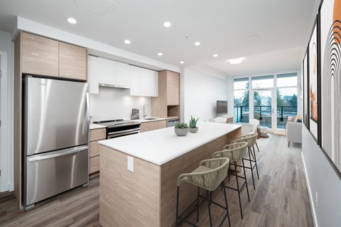 a modern kitchen with a large island and a stainless steel refrigerator