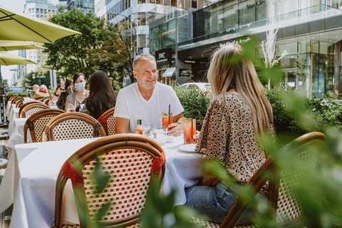 A man and a woman are sitting at a table in an outdoor cafe.