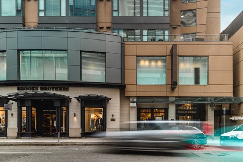 A car is driving past a building with a sign that says Brooks Brothers.