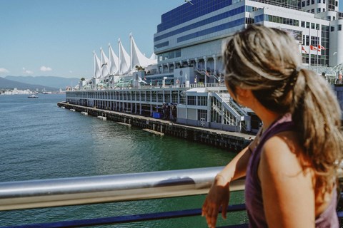 A woman is looking at a pier with a building in the background.