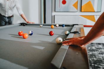 A man is playing pool with a white ball.