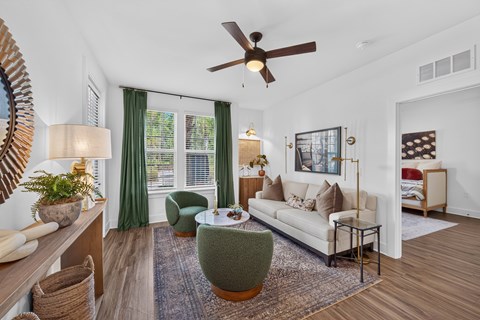 A living room with a white couch, green armchair, and a rug.