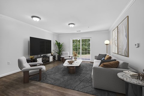 Modern living room with gray sofa and large tv at Glenmont Abbey Village Apartments, Glenmont, 12077