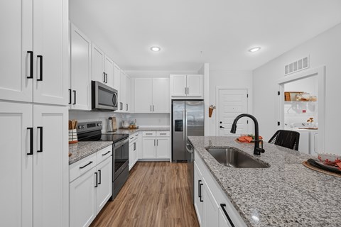 A modern kitchen with white cabinets and a granite countertop.