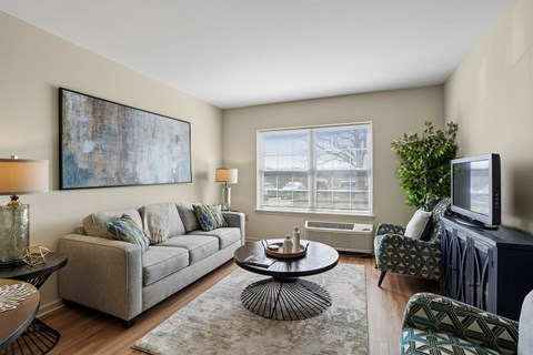 A living room with a grey couch, a coffee table, a television, and a painting on the wall.