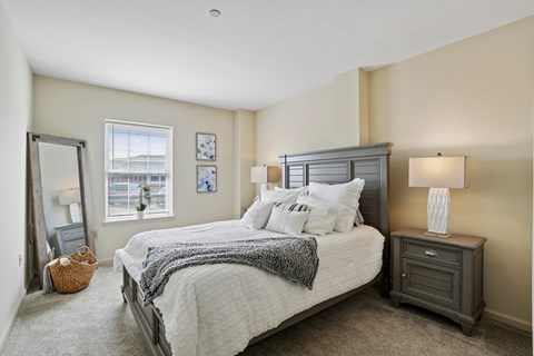 A bedroom with a large bed and a window with blinds.
