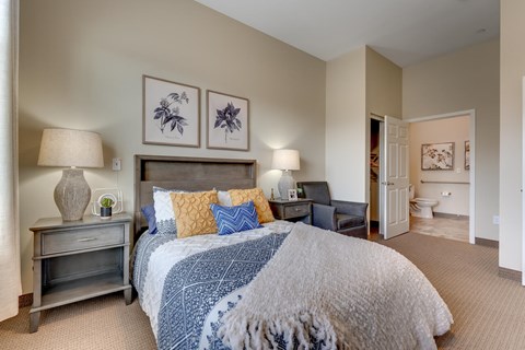 A bedroom with a large bed and a nightstand with a lamp.