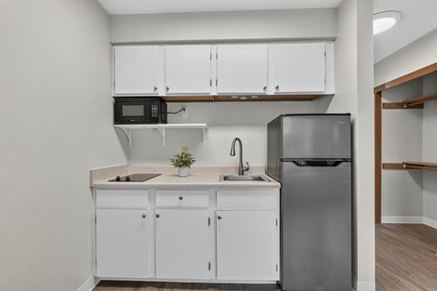 A kitchen with white cabinets and a black fridge.