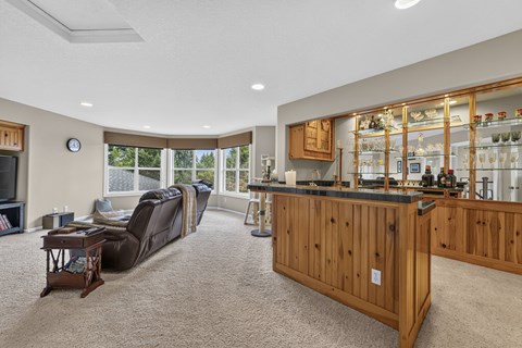 Wet bar with glass display shelving and wood cabinetry at King City Senior Village Apartments, King City, Oregon