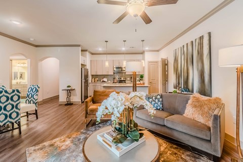 A living room with a grey couch and a coffee table with a vase of flowers on it.