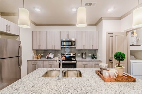 A modern kitchen with a granite countertop and stainless steel appliances.