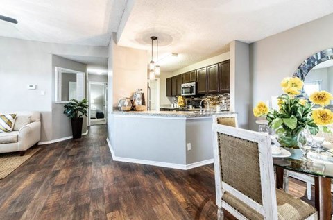 A kitchen with a white counter and brown chairs.