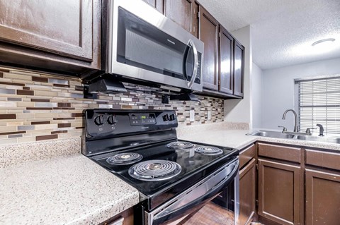 A modern kitchen with a black stove top oven and a microwave above it.